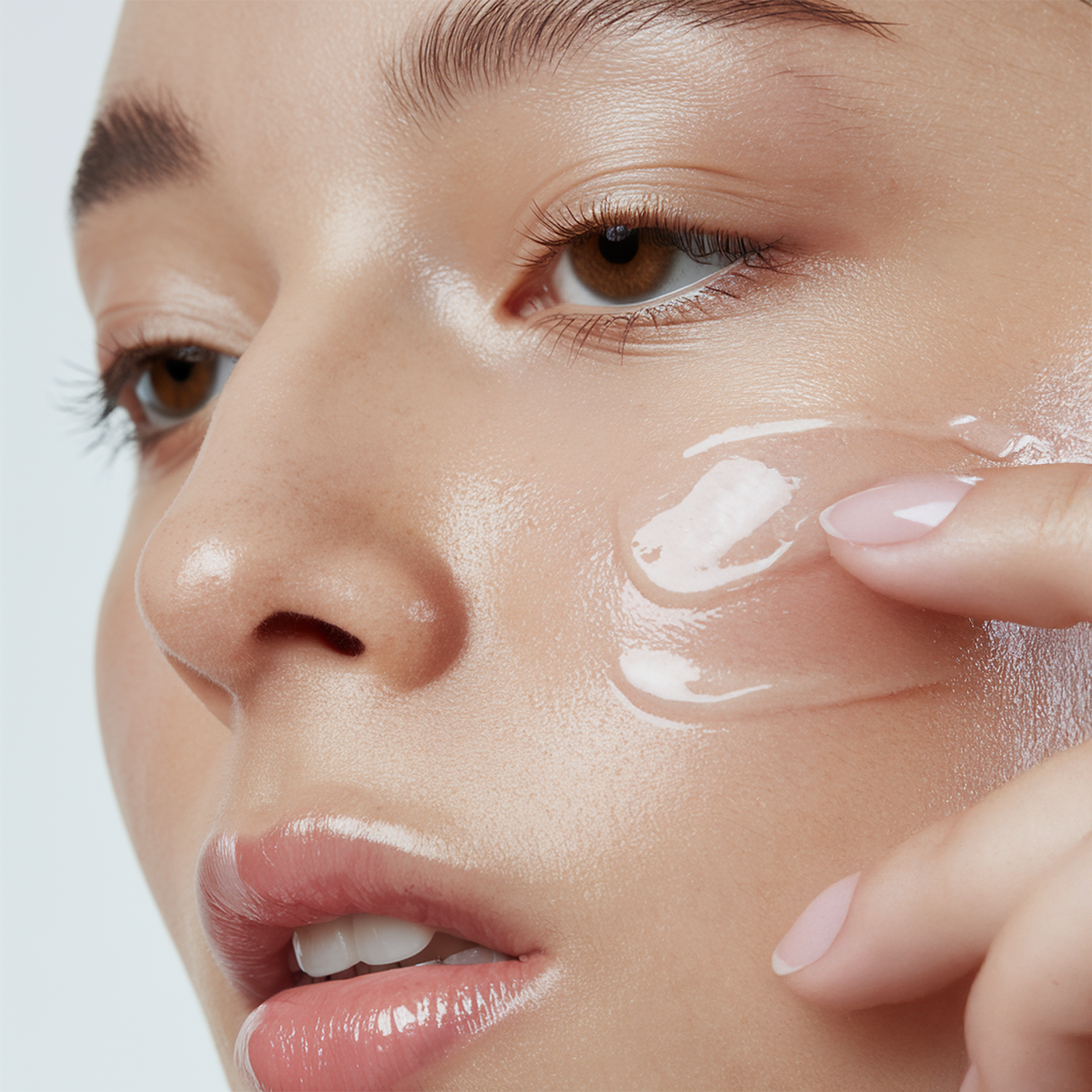 Close-up of a woman applying Advanced Snail Mucin Essence under her eye with her fingertip