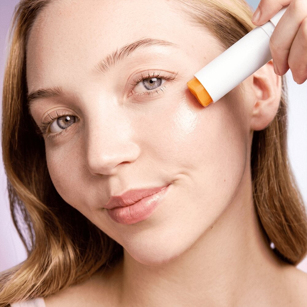 Woman swiping the Radiance Under Eye Balm stick along her cheekbone beneath the eye