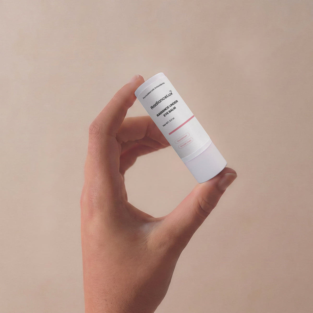 Fingers holding the Radiance Under Eye Balm stick against a tan background