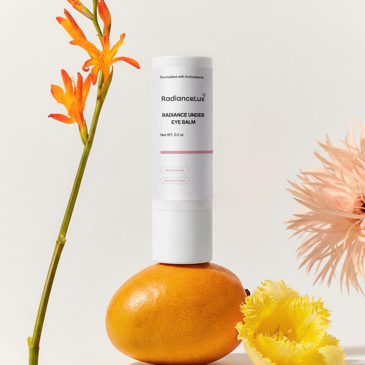 Radiance Under Eye Balm stick balanced on a mango beside orange and yellow flowers